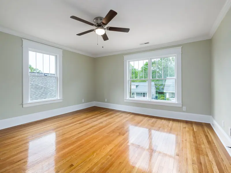 Bright empty living room with a ceiling fan and large windows
