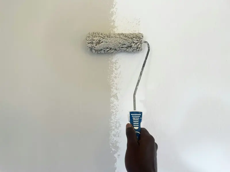 Hand rolling fresh white paint onto an interior wall