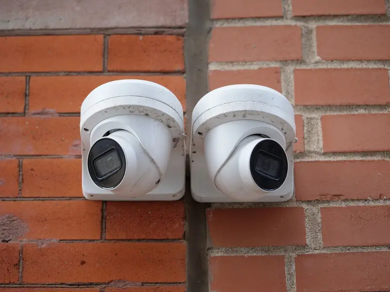 Two white dome security cameras mounted on a brick wall