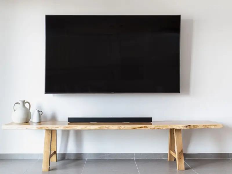 Flat-screen TV mounted on a white living room wall above a wooden media console